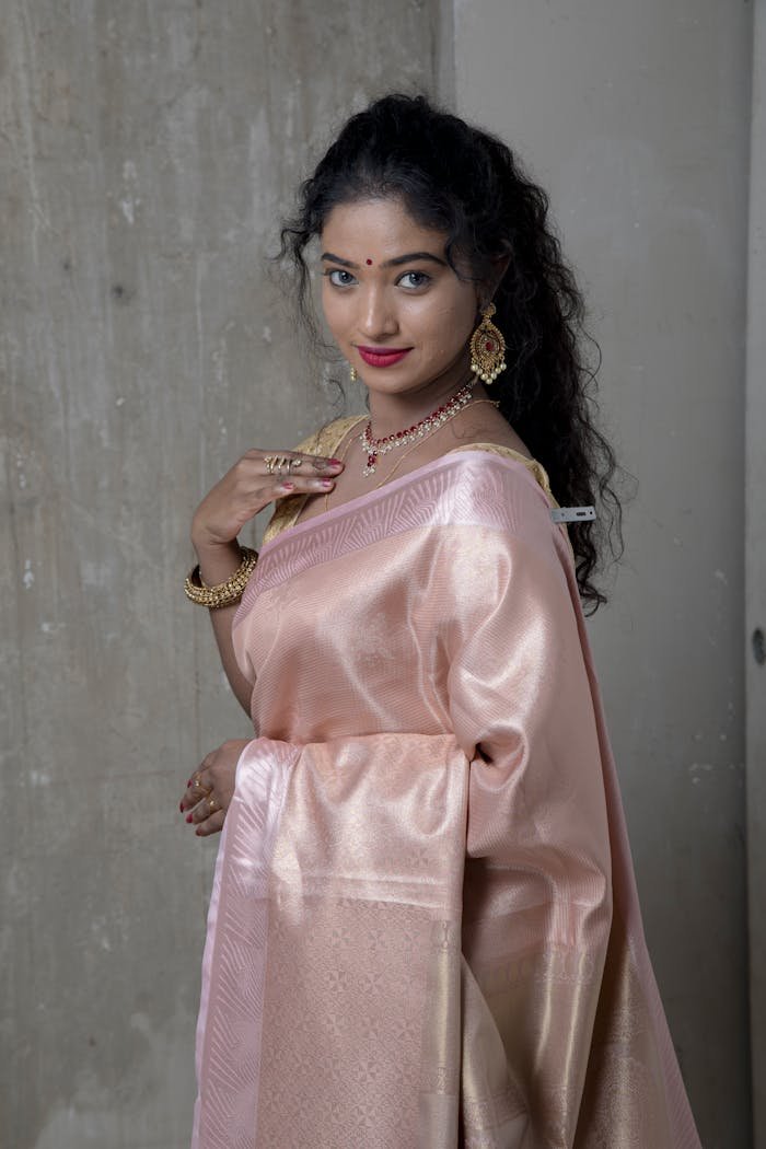 Beautiful woman wearing a pink silk saree and jewelry, showcasing traditional Indian attire.