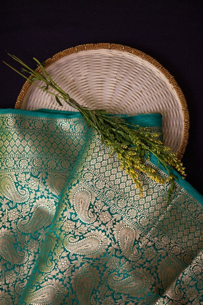 Close-up of a traditional Indian saree with intricate golden paisley patterns and floral decor.